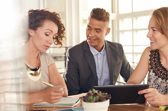 Image of three succesful business people using a tablet during at meeting