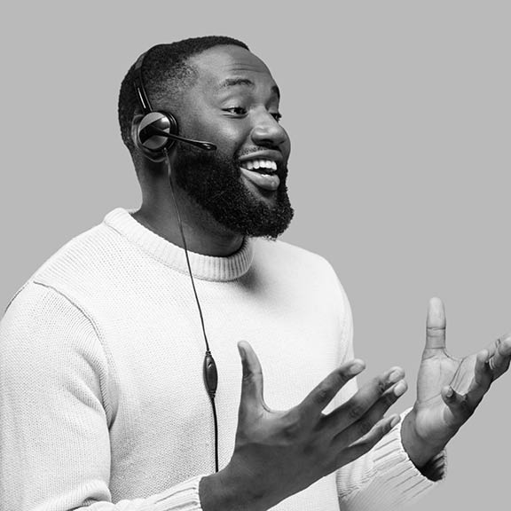 Afro-american call center worker with headphones in casual wear standing on a pink isolated background while communicating with a client and smiling