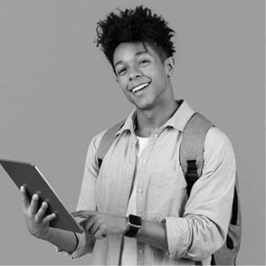 Happy black male student with digital tablet and backpack standing against yellow background, representing the integration of technology in education