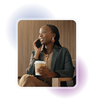 Employee smiling while talking on a mobile phone and holding a takeaway coffee