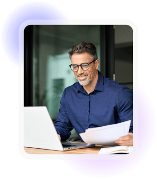 Professional reviewing documents while working on a laptop