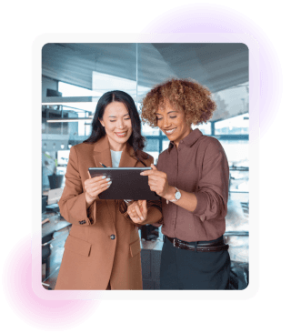 Two colleagues smiling as they review information together on a tablet
