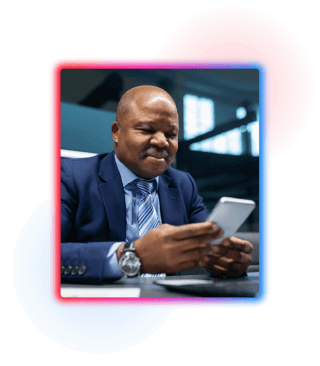 A business man in office wear sat at a desk looking at his phone