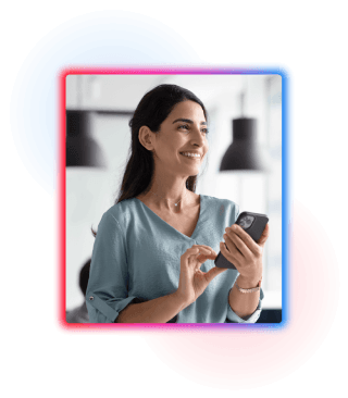 A woman in smart attire stood holding her phone with a smile on her face