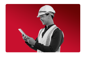 Man in construction uniform looking at an iPad on a red background.