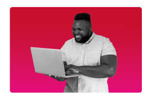 A man smiling holding and looking at a laptop.