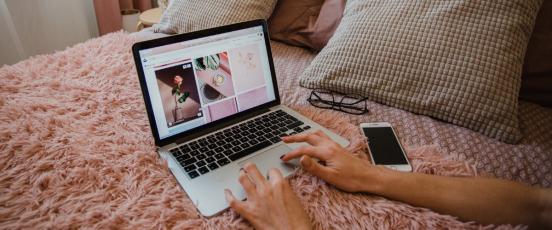 Person working from home crouched on bed with laptop