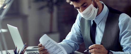 Man at desk with paperwork wearing mask