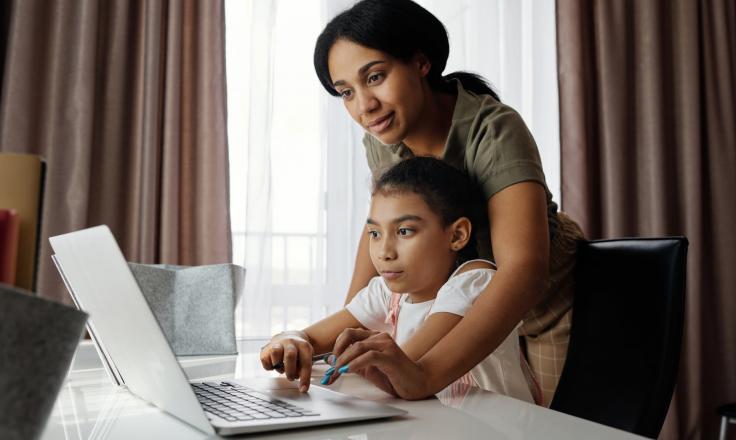mother helping daughter use her laptop