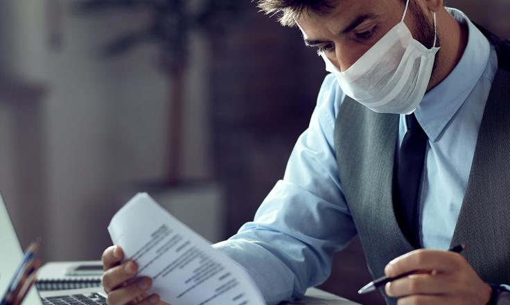 Man at desk with paperwork wearing mask