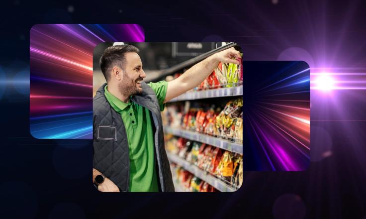 A smiling man in a green supermarket uniform restocking a shelf.