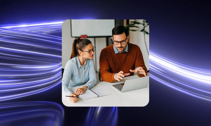 Two payroll employees at a small business talking over a laptop.