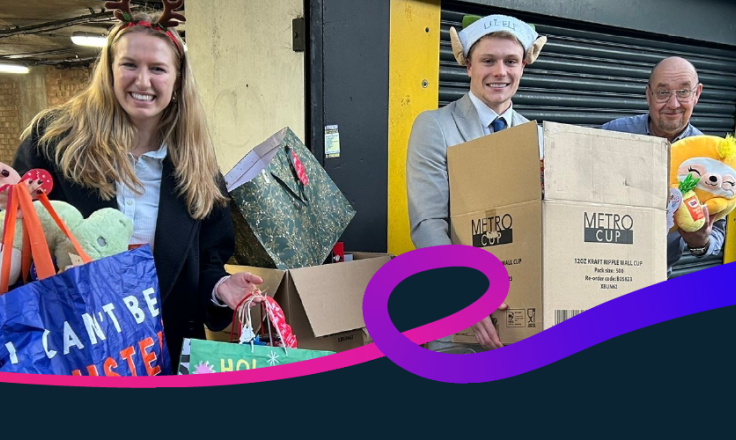 Three people holding gifts outside a donation drop off point at Christmas