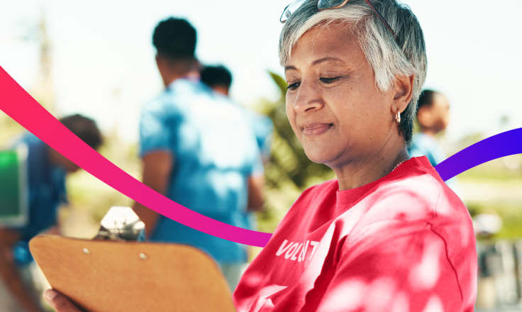 Volunteer looking at clipboard with other volunteers in the background