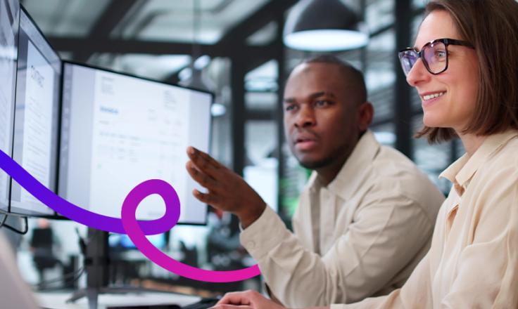 A man and woman working at a desk looking at computer screens.