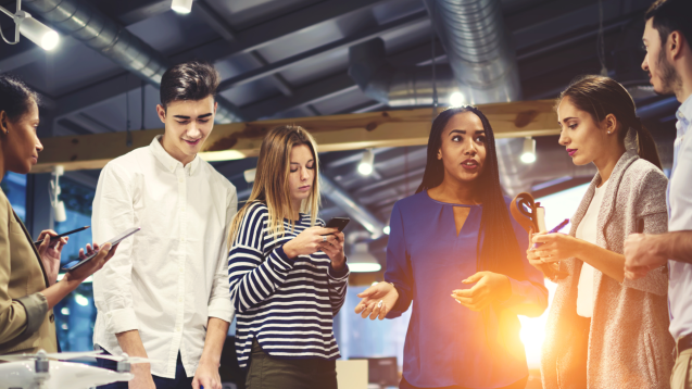 Group of people looking at phones and talking