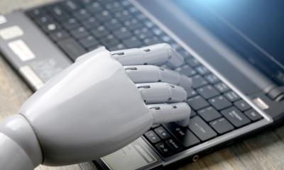 Robot hand typing on a laptop keyboard