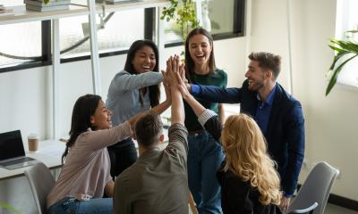 Employees gathered in a circle high-fiving, representing an engaged time