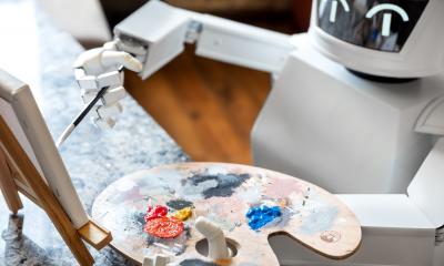 Robot pictured with an easel and paint palette, painting a picture representing AI art