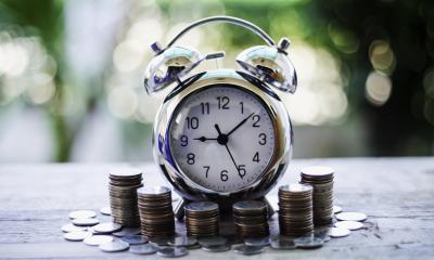 Alarm clock pictured around coins signifying that time is money