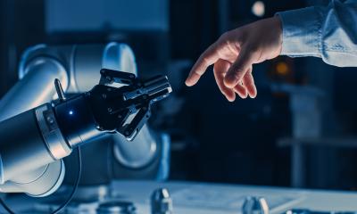 Human hand reaching out to a robot arm, representing the relationship between humans and AI