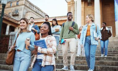 nine university students holding books, walking down steps.