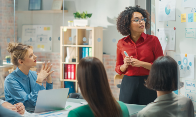 a lady wearing glasses, and a red blouse, presenting a new go to market strategy in product marketing.