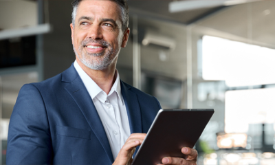 a man stood in an office, using a tablet accessing MHR's finance software integrations.