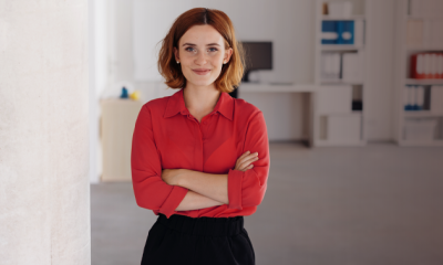 A lady stood in an office, with her arms crossed.