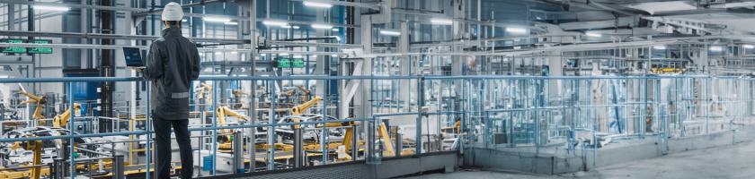 A worker in a manufacturing facility, overseeing the automated building of products