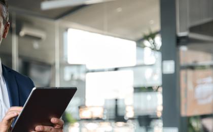 a man smiling holding an ipad, happy after choosing MHR for their finance integration.