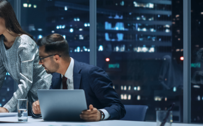 three people working together in an office in a skyscraper, discussing financial reporting.