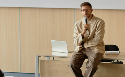 person sat at desk giving lecture