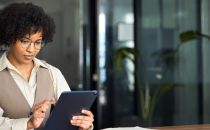 a lady sat at an office table working on a laptop improving her companies employee experience with MHR's People platform.