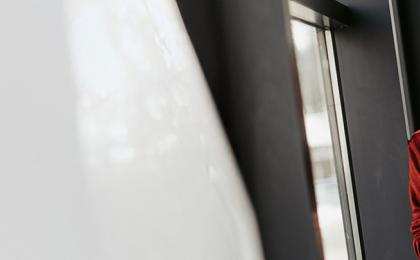 A lady holding a tablet looking out a window.