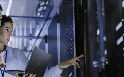 man and woman looking at a laptop and data servers