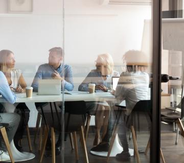 A group of people sat around a board table in an office environment