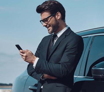 Man standing against car looking at mobile phone