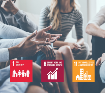group of people in a meeting with UN SDGs 1, 8 and 11 on top