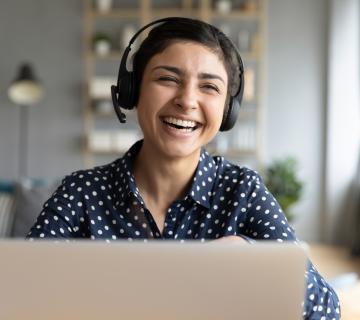 woman smiling working on a laptop with a headset