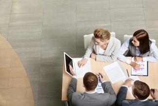 Four business professionals sitting around a desk in an office setting