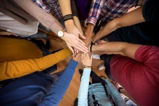 group of people putting hands in the centre