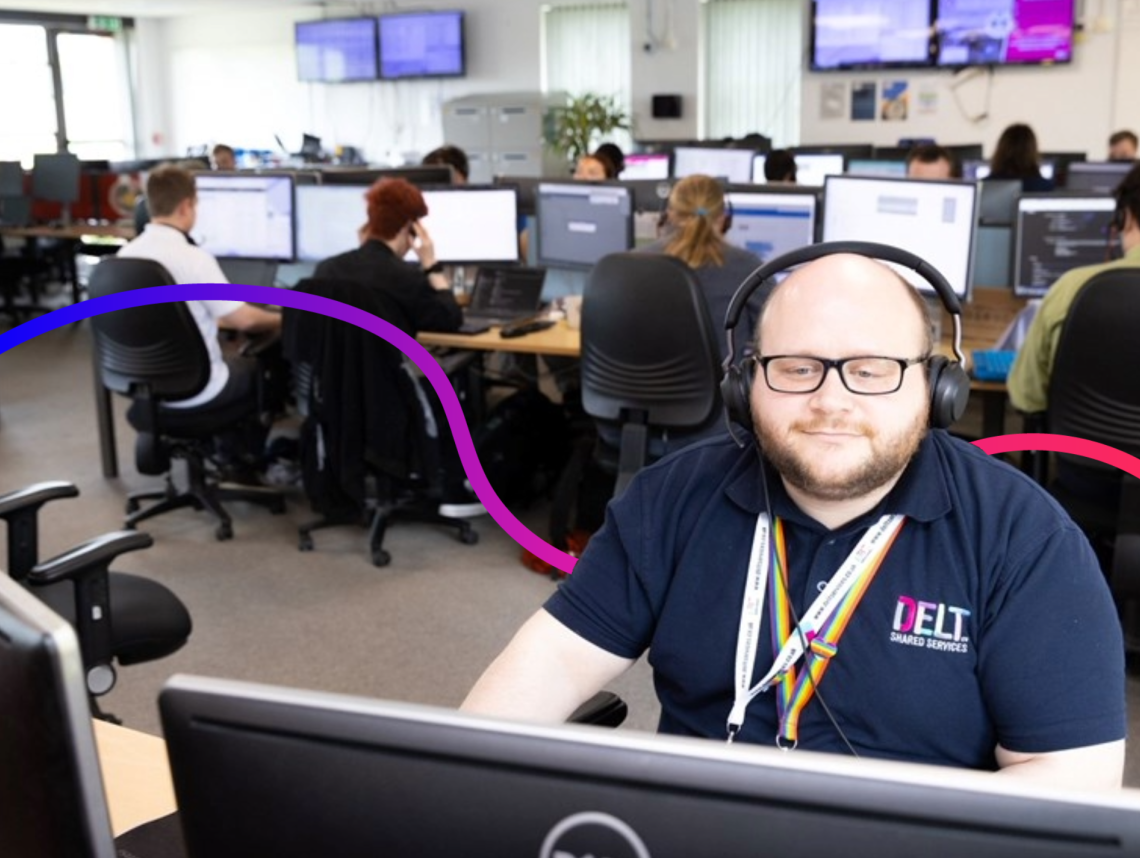 Man at a computer wearing a delt shared services uniform