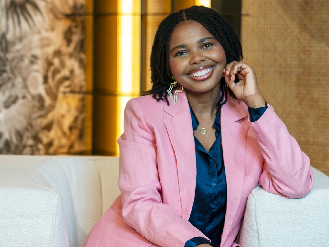 Maphrida Wehrli sits on a white sofa wearing a pink jacket.