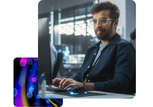 A man sat at a desktop, wearing glasses.