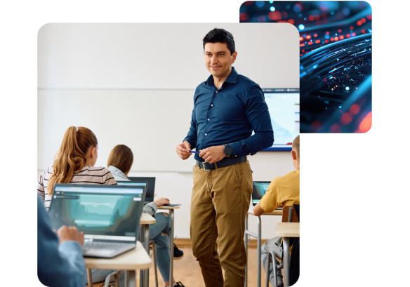 a man stood in between multiple desks with people working on laptops.