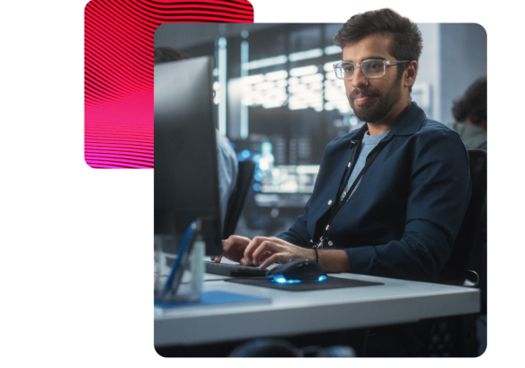 A man working on a desktop, wearing glasses.