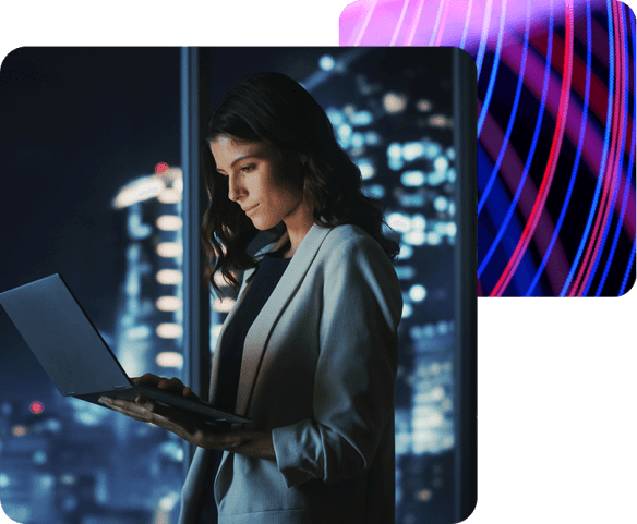 a lady standing next to a window, working on a laptop.