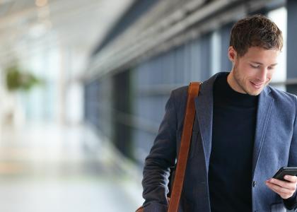 Smartly dressed smiling employee in hallway on mobile phone