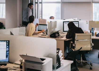 Inside an office with workers sitting and talking at desks